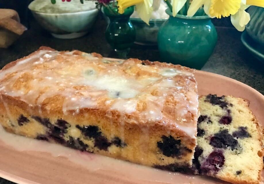 A loaf of blueberry bread on a wooden board.