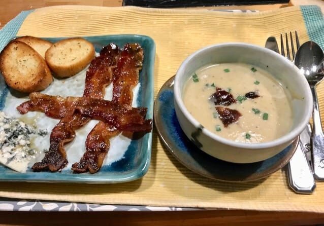 A bowl of soup and bacon on a plate.