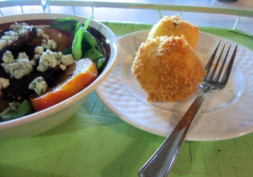 A bowl of salad and some fried food on a plate.