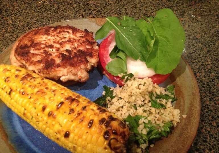 A plate of food with corn, rice and salad.