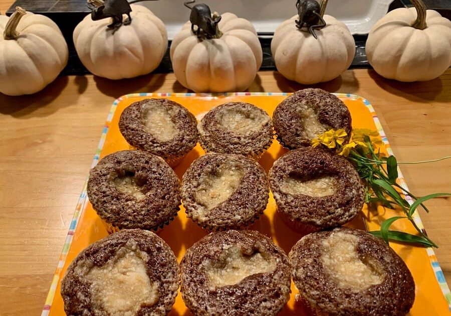 A tray of cupcakes with chocolate frosting and other pumpkins.