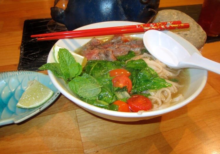 A bowl of noodles with meat and vegetables.