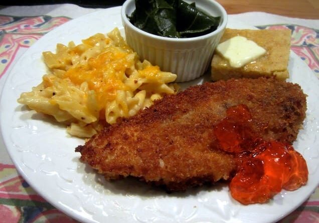 A plate of food with meat, macaroni and cheese, and spinach.