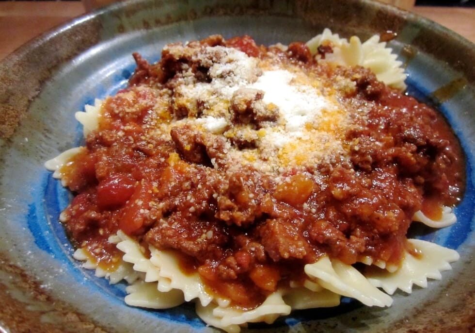 A plate of pasta with meat sauce and cheese.