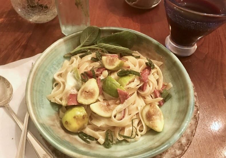 A bowl of pasta with vegetables on the side.