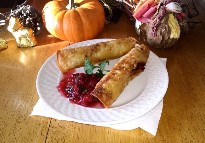 A white plate topped with two pastries covered in sauce.