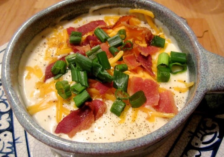 A bowl of food with cheese, bacon and green peppers.