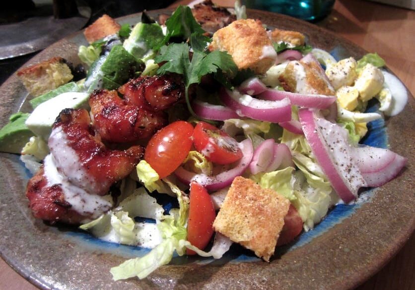 A plate of salad with meat and vegetables.