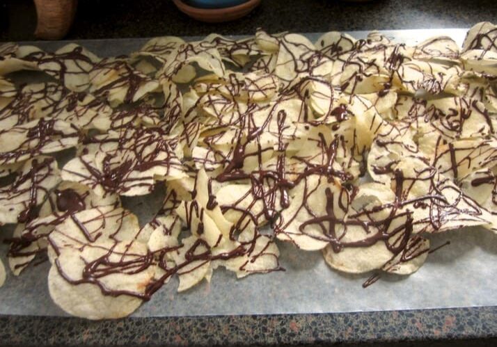 Chocolate dipped potato chips on a baking sheet.