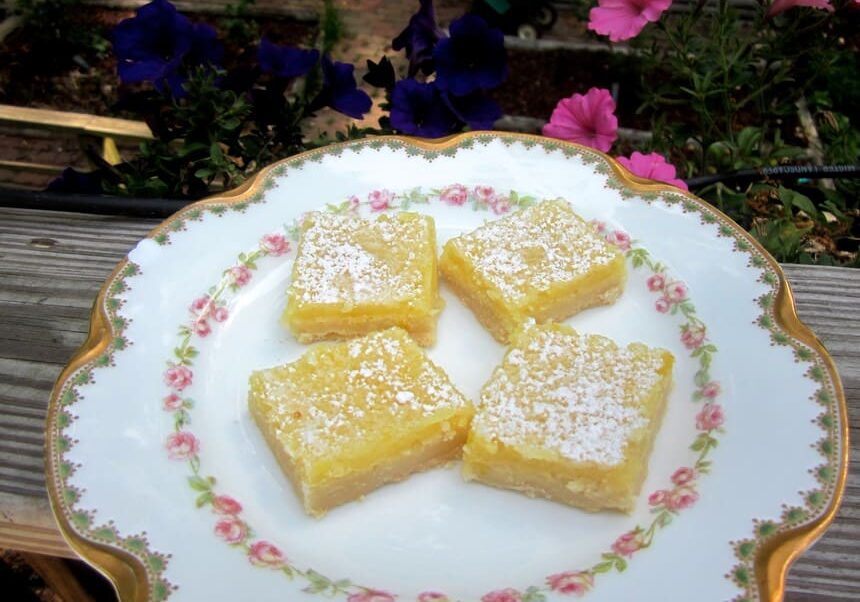 A plate of lemon bars on top of a table.