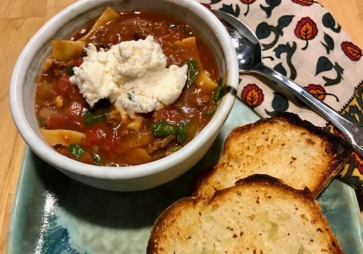 A bowl of soup with bread on the side.