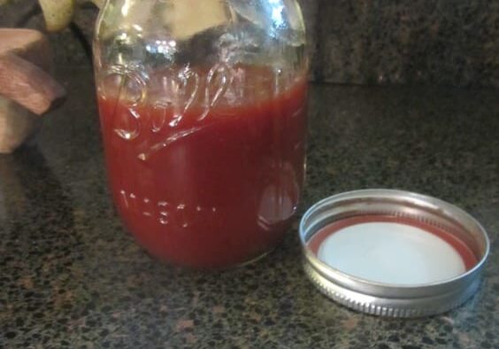 A jar of ketchup and a container with a lid.