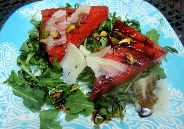 A plate of food with watermelon and greens.