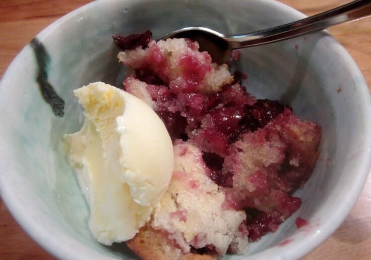 A bowl of food with ice cream and berries.