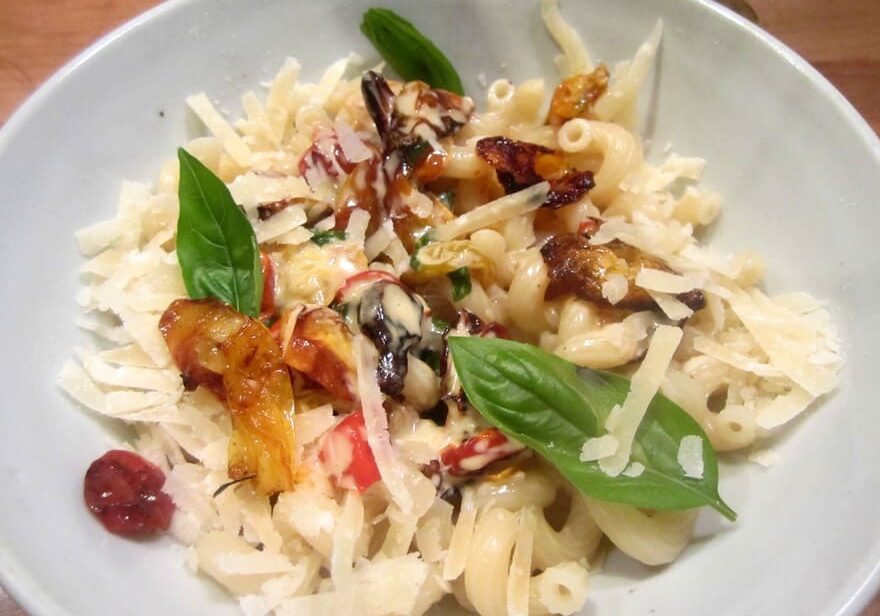 A bowl of pasta with some vegetables and cheese