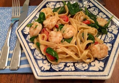 A plate of pasta with shrimp and tomatoes.