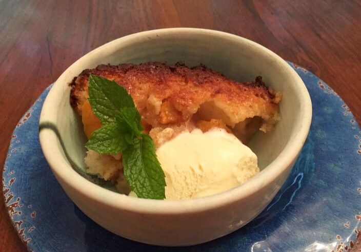 A bowl of food with ice cream and mint leaves.