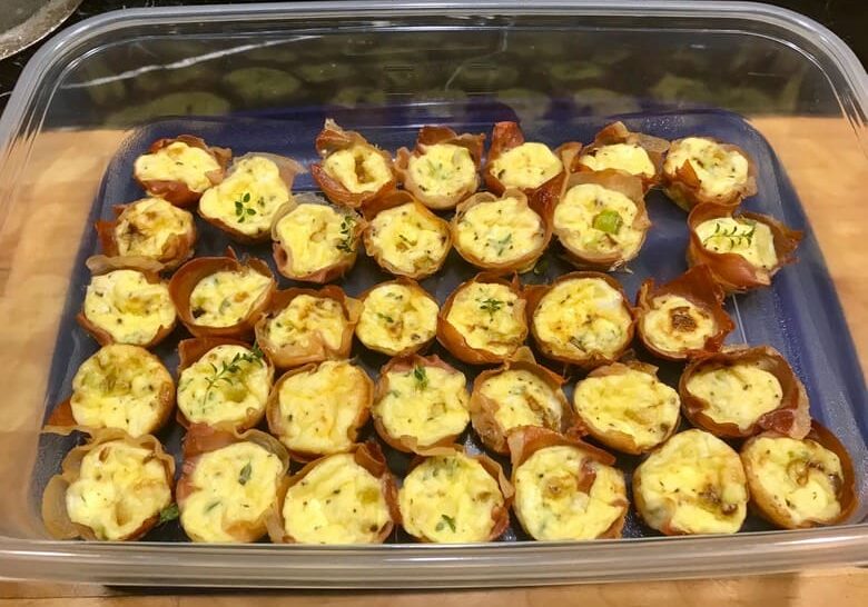 A tray of baked potatoes with cheese and herbs.