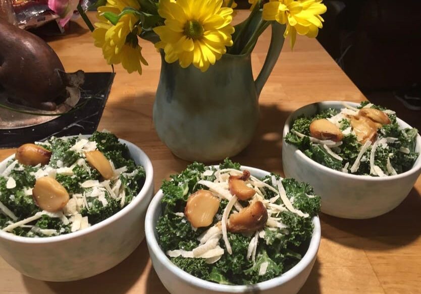 Three bowls of food on a table with flowers.